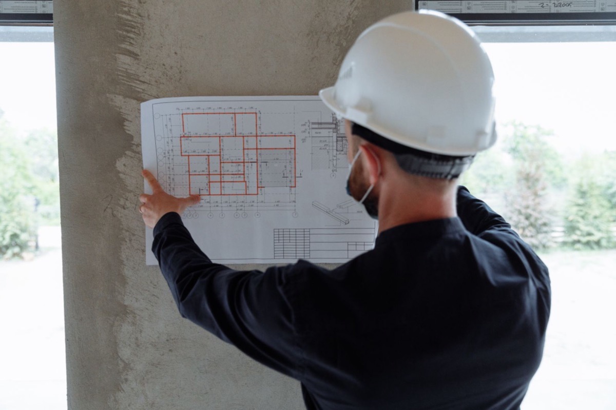 Engineer in a hard hat reviewing floor plans at a construction site