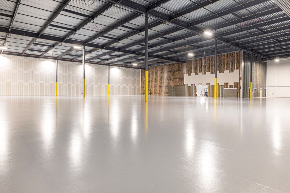 Empty modern warehouse interior with a glossy coated resin floor and open span
