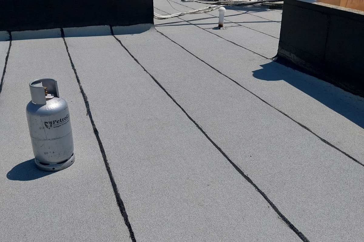 Grey mineral-finish waterproofing membrane covering a flat concrete roof deck